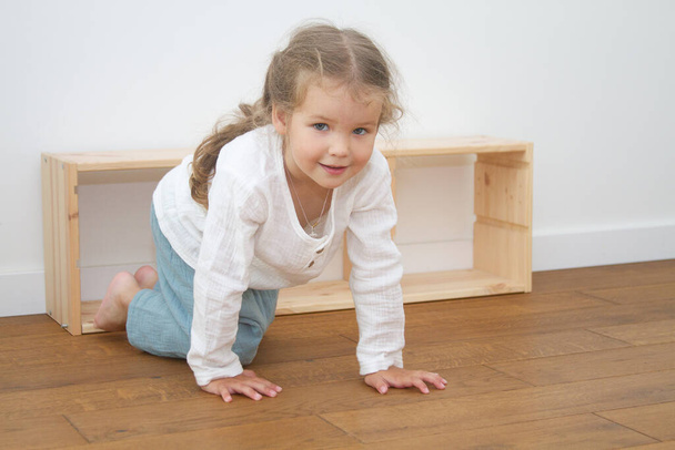 Little cute girl in a bright room, a minimum of objects in the room - Photo, Image