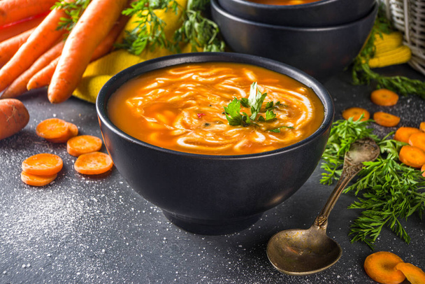 Lahodná domácí smetanová mrkvová polévka. Zeleninové mrkvové polévkové pyré na tmavě šedém stole s čerstvým mrkví kopírovat prostor - Fotografie, Obrázek