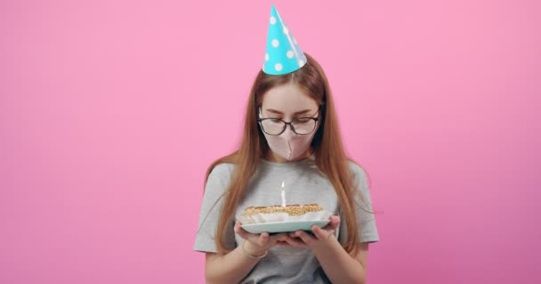 Birthday girl blowing off candle on cake in medical mask - Filmmaterial, Video