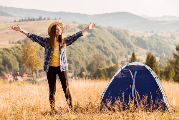 Happy freedom girl in straw hat with hands up in mountains camping travel - Zdjęcie, obraz