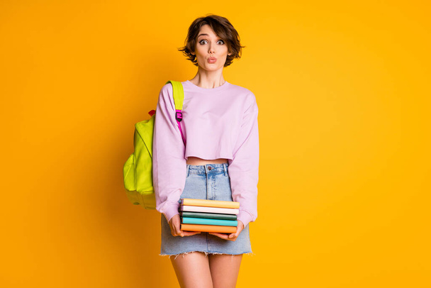 Portrait of childish playful high school girl impressed book pile stack she get library make lips pouted plump have bag wear pink jeans sweater isolated over bright shine color background - Foto, Imagen