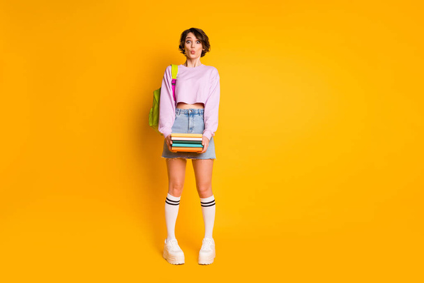 Full length body size view of her she nice attractive lovely pretty funny shy girl carrying academic materials pout lips posing isolated on bright vivid shine vibrant yellow color background - Foto, Imagem