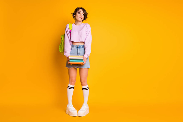 Full length body size view of her she nice attractive lovely unsure doubtful shy girl carrying academic materials new semester year isolated on bright vivid shine vibrant yellow color background - Fotografie, Obrázek