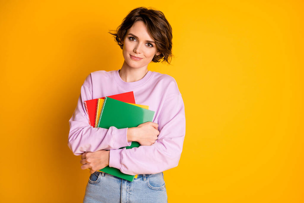 Portrait of her she nice attractive lovely pretty content cheery girl holding in hands educational materials courses classes isolated on bright vivid shine vibrant yellow color background - 写真・画像