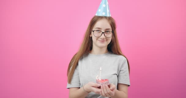 Smiling girl in birthday cap holding cake with candle - Video