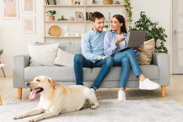 Giovane coppia felice seduta sul divano con il loro cane - Foto, immagini