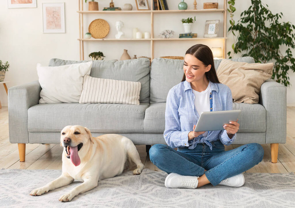 Young woman at home with a tablet and labrador - Foto, Bild