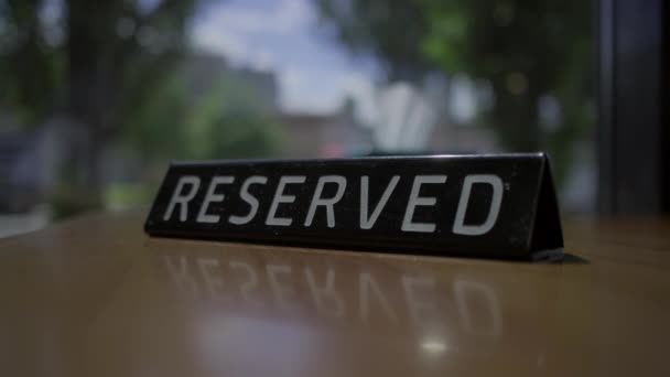 RESERVED sign placing on the cafe table with city view window. The table is reserved. Female hand put RESERVED tag on the table. - Metraje, vídeo