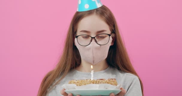 Disappointed girl in medical mask holding birthday cake - Video