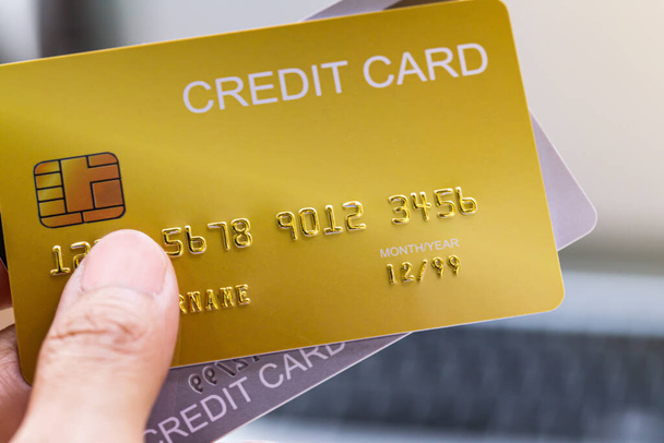 χέρι κρατώντας demo πιστωτική κάρτα online πληρωμή μέσω θολή notebook ή laptop φόντο. - Φωτογραφία, εικόνα