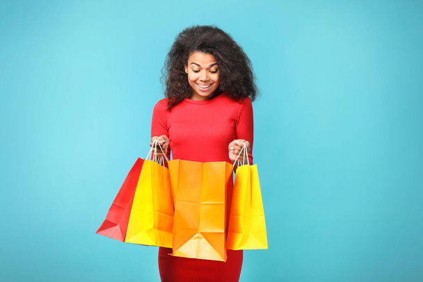 Portrait of a beautiful african woman with shopping bags on blue background - Fotoğraf, Görsel