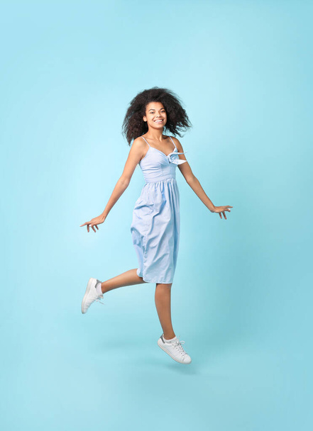 Kaunis afrikkalainen nainen hyppää sinisellä taustalla - Valokuva, kuva
