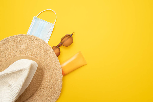 太陽の保護対象。麦藁ビーチ帽子、サングラス、保護spfクリーム、明るい黄色の背景に外科用マスク。ビーチアクセサリー。夏の旅行の休暇コロナウイルス隔離の概念.  - 写真・画像