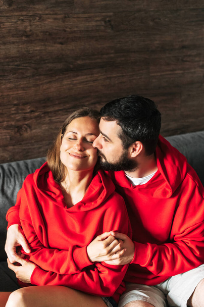 Couple amoureux en sweat à capuche rouge à la maison - Photo, image