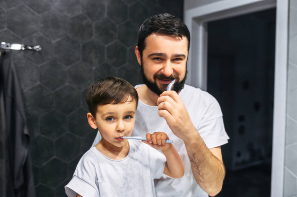 Father and toddler brush their teeth together - Foto, afbeelding