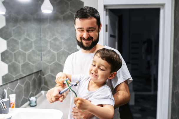 Father and toddler brush their teeth together - Foto, afbeelding