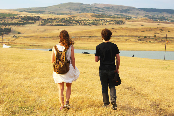 junger Mann und Frau zu Fuß im Tal im Sommer in Tiflis, Georgien.. Foto von hinten aufgenommen. - Foto, Bild