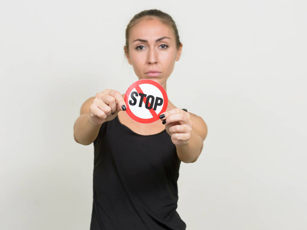 Young woman with brown hair showing stop sign - 写真・画像