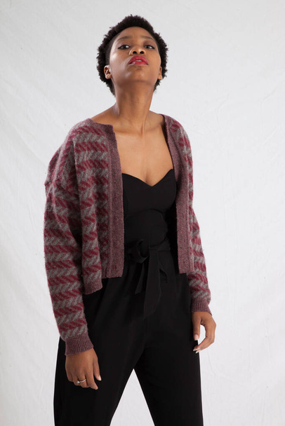 Gyönyörű fekete nő keres töprengő egy fekete ruhát és kabátot - Fotó, kép