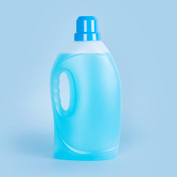 Waschmittelflasche auf blauem Hintergrund. Plastikbehälter mit Reinigungsprodukten, Haushaltschemikalien oder flüssigem Waschmittel. Wäschetag, Reinigungskonzept - Foto, Bild
