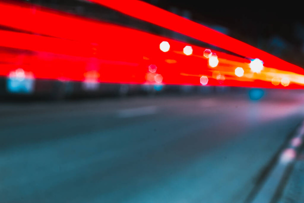 Two red blurry speed trails from a busy traffic in the city at night with white bokeh spot lights Abstract and futuristic background from fast moving cars in town - Zdjęcie, obraz