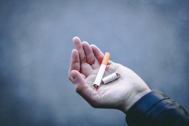 Mladý člověk ruka drží cigaretu, která je rozbitá ve dvou Toxický nezdravý zvyk, který může způsobit rakovinu a další nemoci Koncepce image pro přestat kouřit a bez kouření den - Fotografie, Obrázek