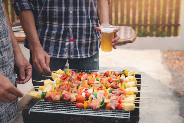 Een man die varkensvlees grilt en barbecuet op een etentje. Voedsel, mensen en familie tijd concept. - Foto, afbeelding