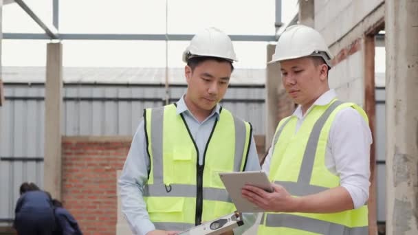 Hombres con sombreros discutiendo el proceso de trabajo en el sitio de construcción - Metraje, vídeo