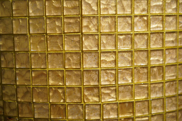 Golden glass checkered texture or abstract geometric mesh pattern or background. Golden-colored glass or mosaic smalt with yellow filling of seams - Photo, image