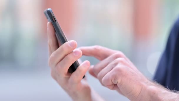 Nahaufnahme der Hände eines Mannes mittleren Alters im Freien mittels Smartphone - Filmmaterial, Video