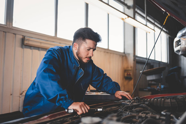 Pensive auto mechanic looking for engine malfunction problem. Car repair concept - Photo, Image