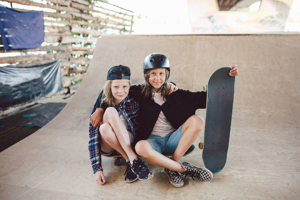 Ομάδα φίλων αθλητές skateboarders ποζάρουν μαζί σε ένα πάρκο skate. Καυκάσια παιδιά διασκεδάζουν μαζί στον αθλητικό αστικό εξωτερικό χώρο για σκέιτμπορντ. Αθλητικός σύλλογος για παιδιά. - Φωτογραφία, εικόνα