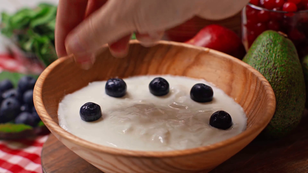 cropped view of man putting fresh blueberries in bowl with yogurt  - Footage, Video