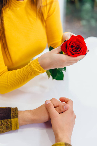 Cropped shot of young people, meeting in cafe on special occasion, boy gave a red rose to his adorable girlfriend. - 写真・画像