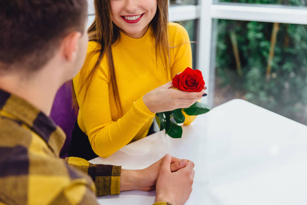 Cropped shot of young people, meeting in cafe on special occasion, boy gave a red rose to his adorable girlfriend. - Foto, immagini