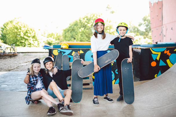 Grupo de amigos atletas de skate posando juntos em um parque de skate. Crianças caucasianas se divertindo juntas em esportes área urbana ao ar livre para skate. Clube de esportes para crianças
. - Foto, Imagem