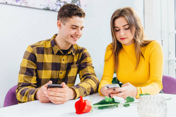 Beautiful young couple is using smartphones to look through social media content and share interesting things with partner. - Fotografie, Obrázek