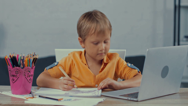 roztomilý chlapec mává rukou, zatímco s videohovor a kreslení doma - Záběry, video