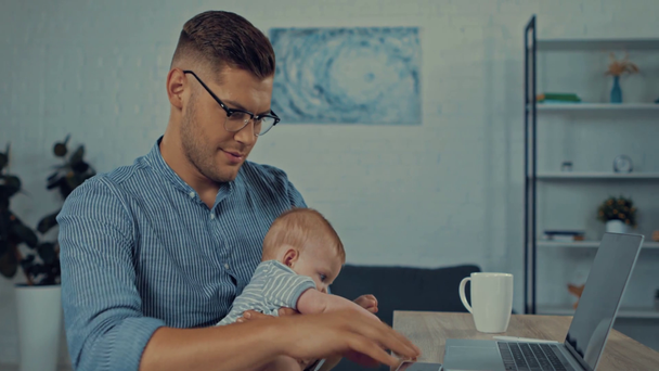 happy father holding in arms infant son and taking selfie - Filmagem, Vídeo