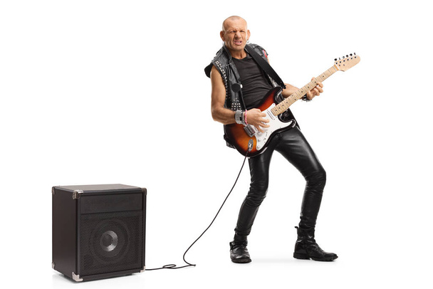 Full length portrait of a rocker playing a guitar plugged into an amplifier isolated on white background - Foto, Imagen