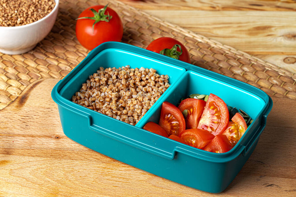 Blue lunch box with buckwheat and tomatoes - Fotó, kép