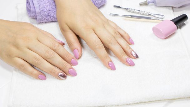 Women's hands with a beautiful manicure on a white background. Manicure. Pink manicure, nail art, glitter Polish. Nude, pastel, trend. Beauty salon, nail care. Hands spa concept. Feminine, makeup. - Foto, imagen