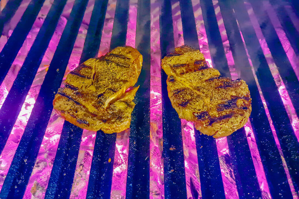 Дві яловичини накладаються на вогняні грилі. М'ясо кладуть на гриль для барбекю. М'ясо стейка з яловичини на грилі на фоні вогню гриля
. - Фото, зображення