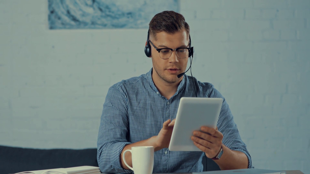 operator in headset drinken van koffie, praten en het gebruik van digitale tablet  - Video