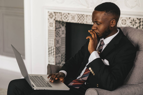 Always make a total effort, even when the odds are against you. African american businessman is working, using his laptop while resting in the cafe - 写真・画像
