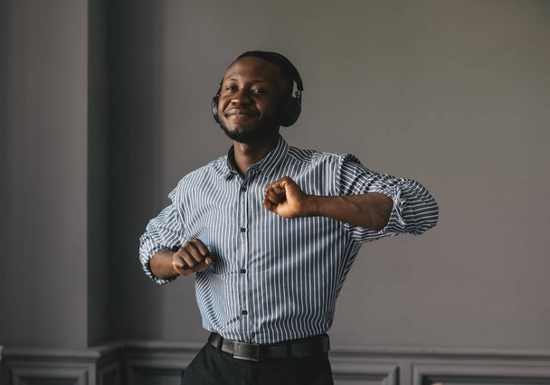 african-american man in stylish shirt in headphones listening music and enjoying music, dancing  - Фото, зображення