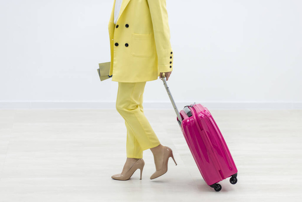 Cropped shot of female carrying a pink suitcase and pssport over white background with copyspace. - Φωτογραφία, εικόνα
