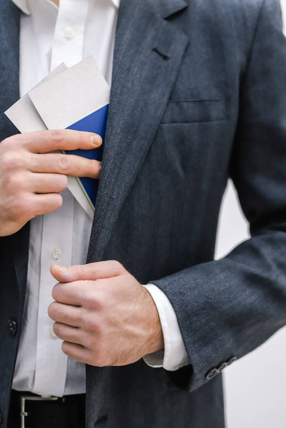Cropped shot of businessman taking travel documents out of the inner pocket of his jacket. - Foto, Imagem
