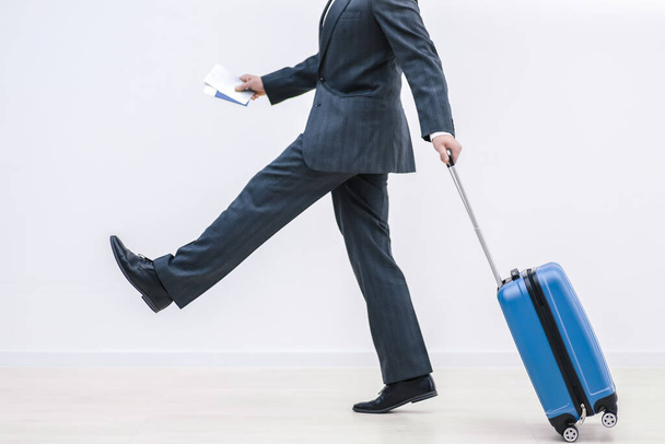 Homme en tenue formelle et avec une valise bleue se dépêche, court. Isolé sur fond blanc. - Photo, image