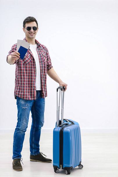Happy smiling male tourist with baggage and travel documents enjoying their summer vacation beginning. - Foto, imagen